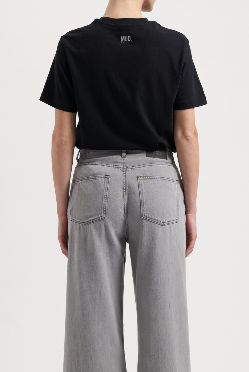 Sustainable MUD Jeans in dark brown, crafted from organic cotton, worn with a white t-shirt and white sneakers.