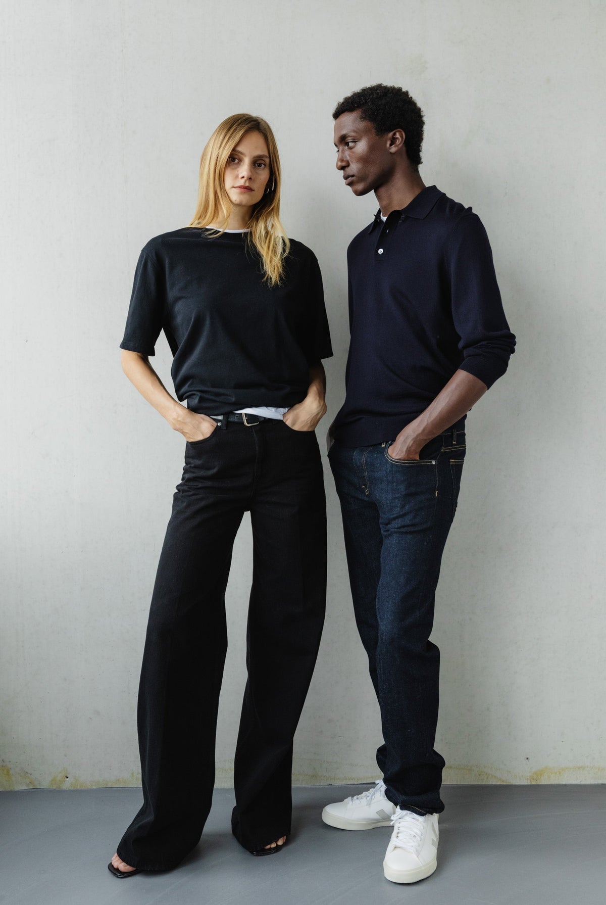 Fashion-forward duo in chic black and navy outfits, showcasing modern casual style in a minimalist setting.