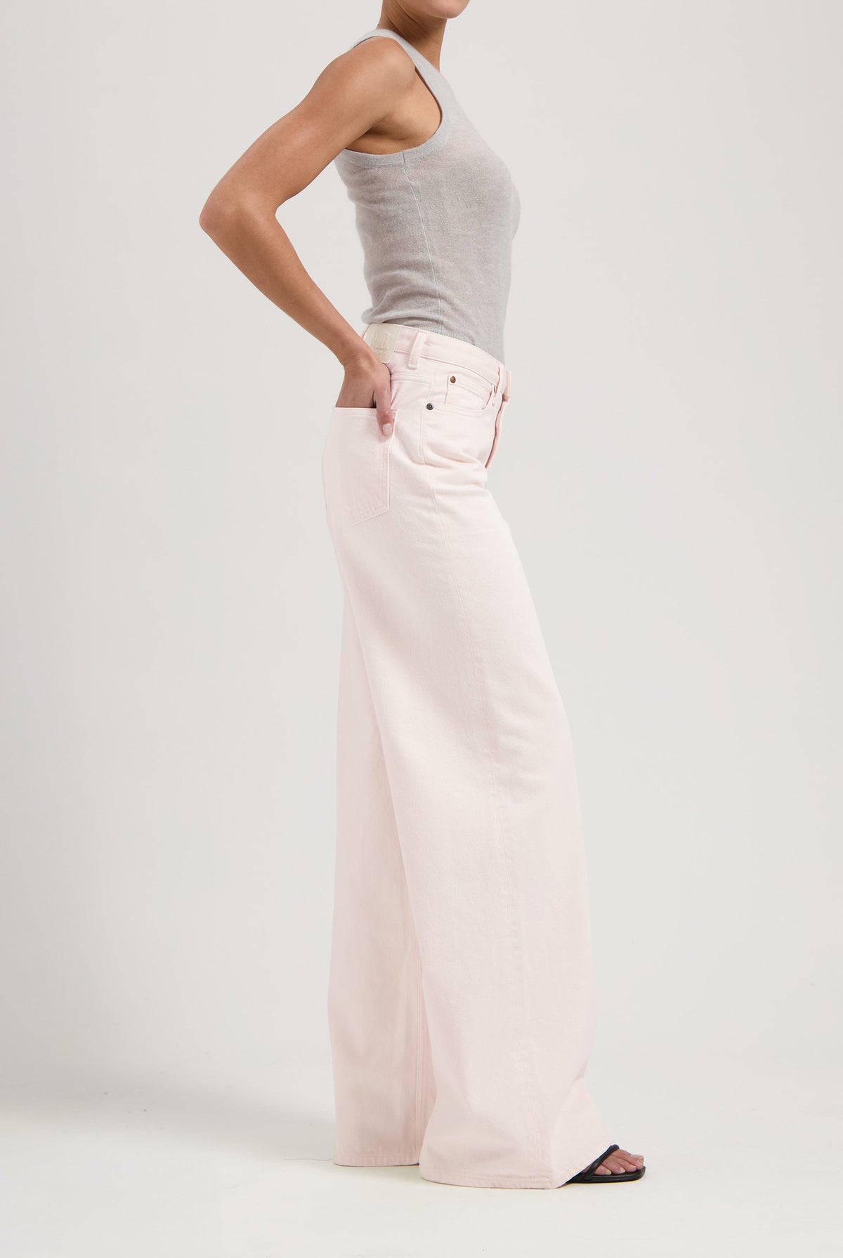 Wide-leg light pink jeans paired with a fitted gray tank top, showcasing a minimalist and modern fashion look.