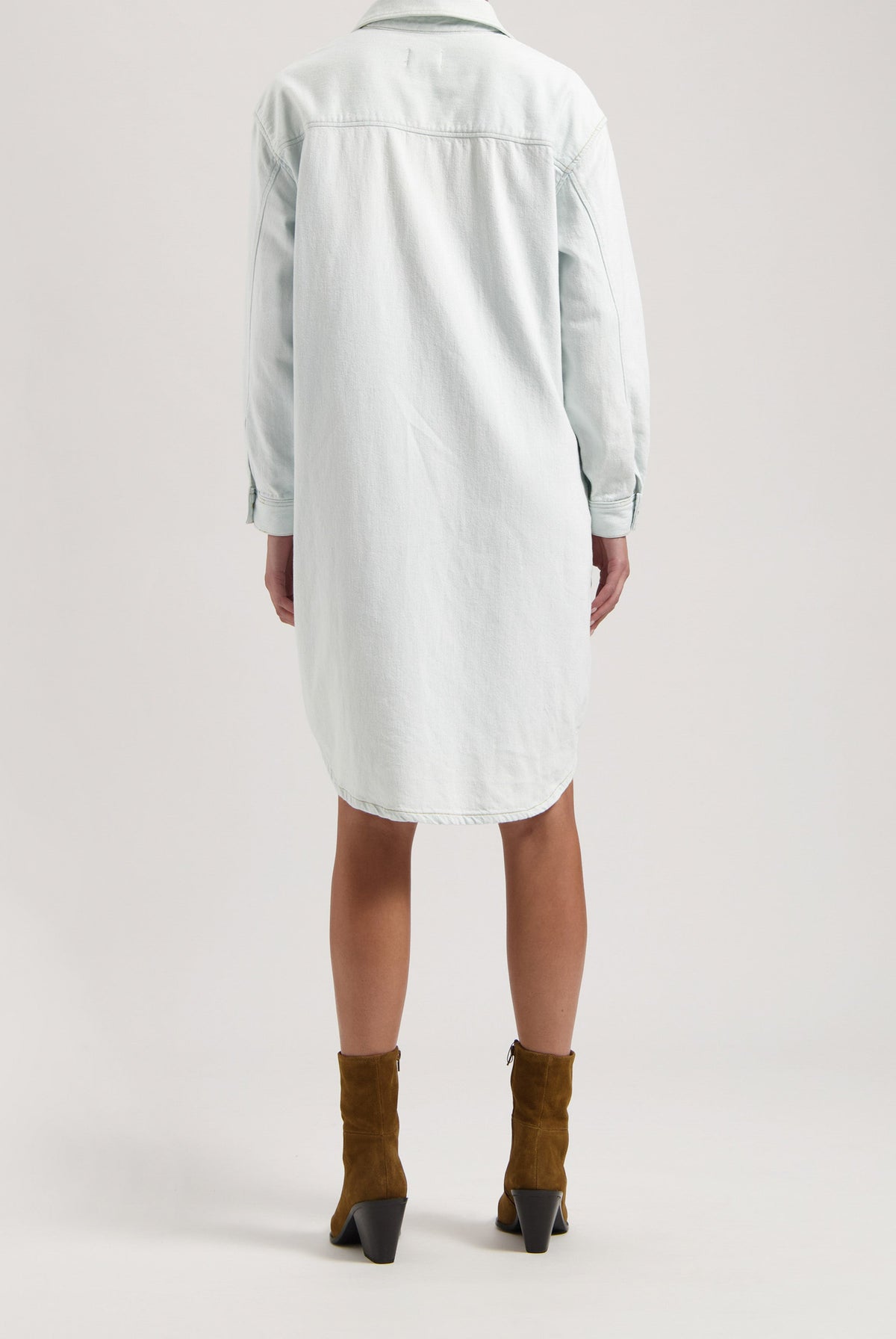 Back view of a light blue denim shirt dress paired with brown suede ankle boots, emphasizing casual style fashion.