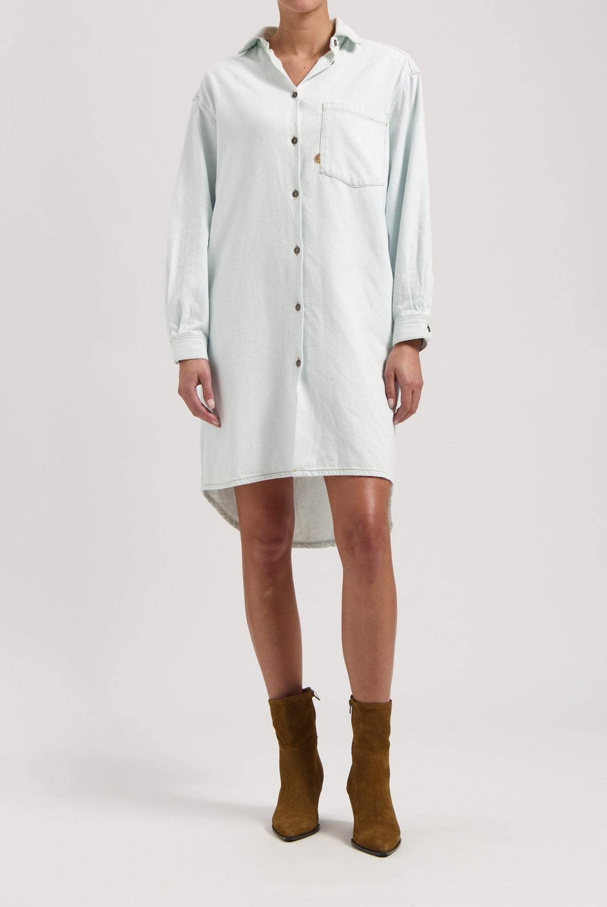 Light blue button-up denim shirt dress with long sleeves, worn with brown suede ankle boots.