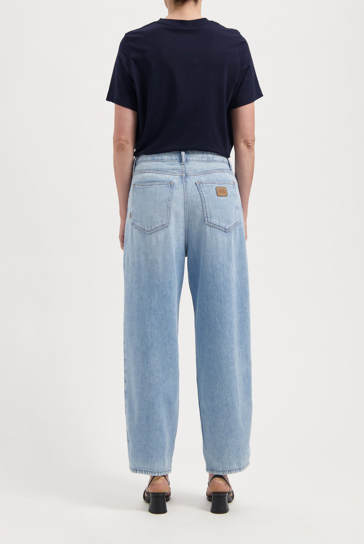 Light blue, wide-leg denim jeans with back pockets, styled with a short-sleeve navy top and open-toe black heels.
