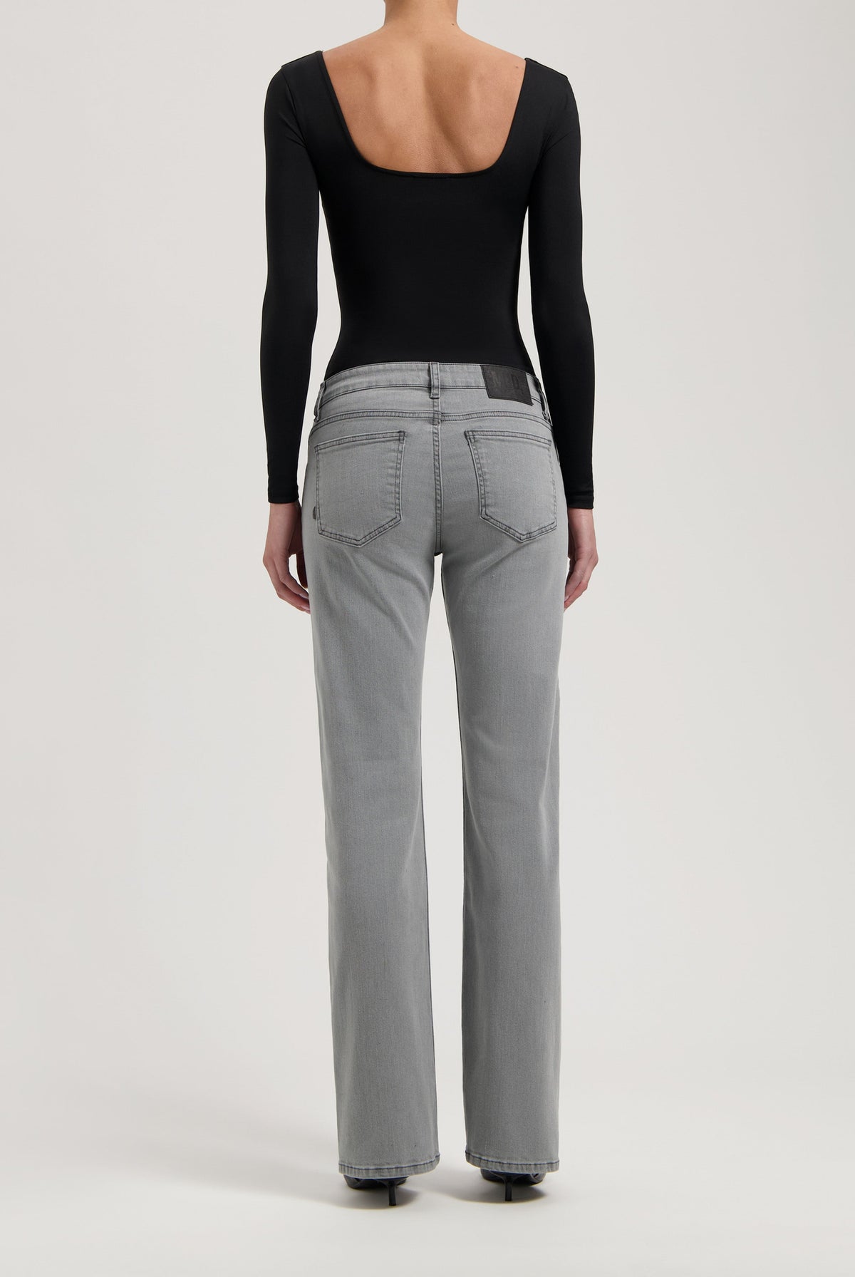 Back view of gray straight-leg jeans paired with a sleek black long-sleeve bodysuit, highlighting casual elegance.