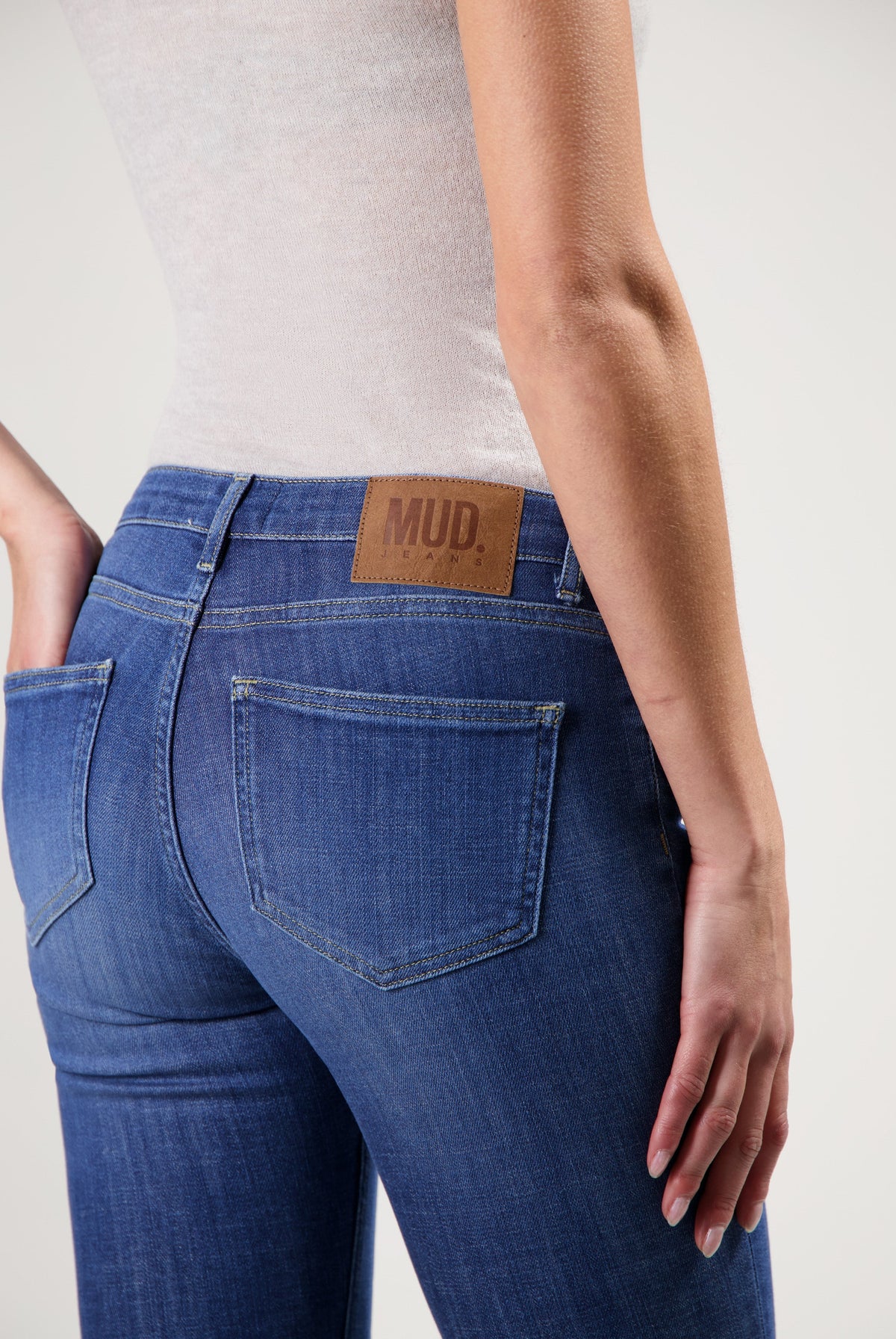 Close-up of MUD Jeans, showcasing a slim-fit design in blue denim, paired with a neutral sleeveless top.