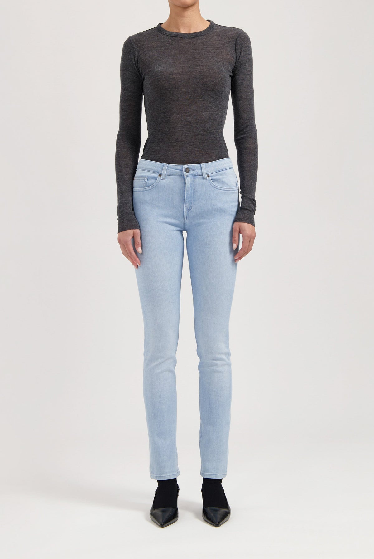 Slim-fit light blue denim jeans with a button closure, paired with a charcoal gray long-sleeve top, modeled standing.