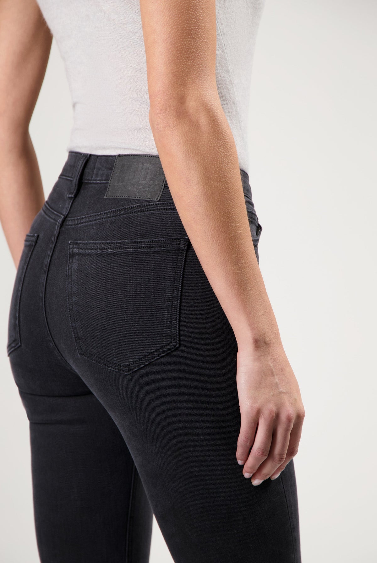 A person wearing sustainable black denim jeans from organic cotton paired with a fitted white sleeveless top.