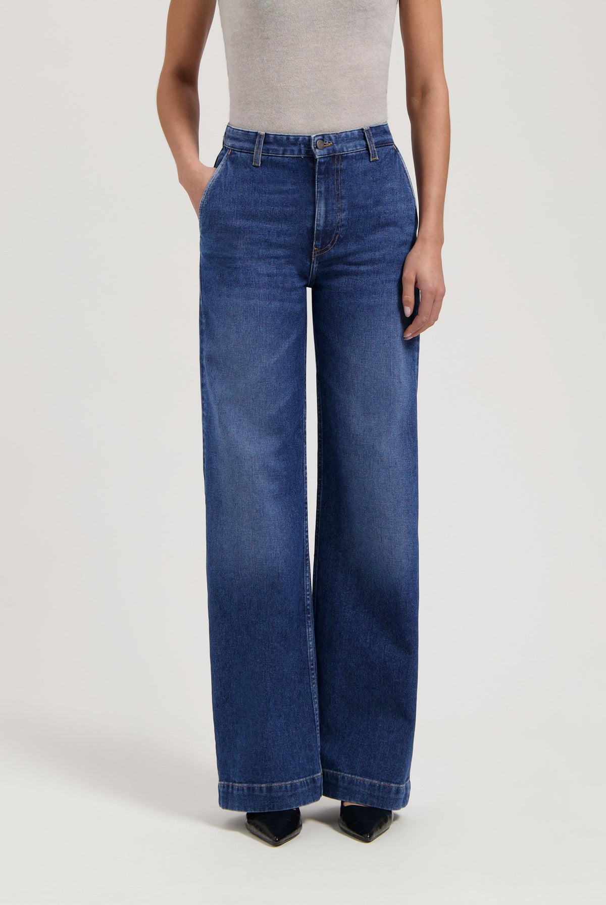 High-waisted blue wide-leg jeans made from denim, paired with a gray sleeveless top, showcasing casual chic fashion.