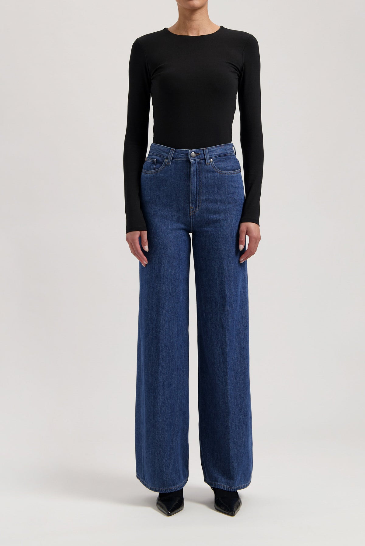 A stylish outfit featuring high-waisted, wide-leg blue jeans paired with a fitted, long-sleeve black top.