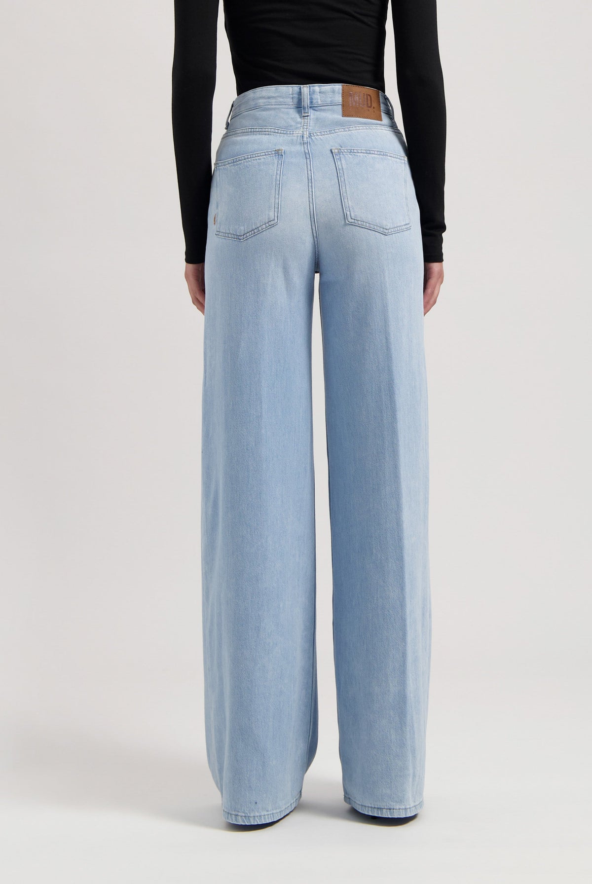 Wide-leg light blue denim jeans with a high waist and sustainable materials, paired with a fitted black top.