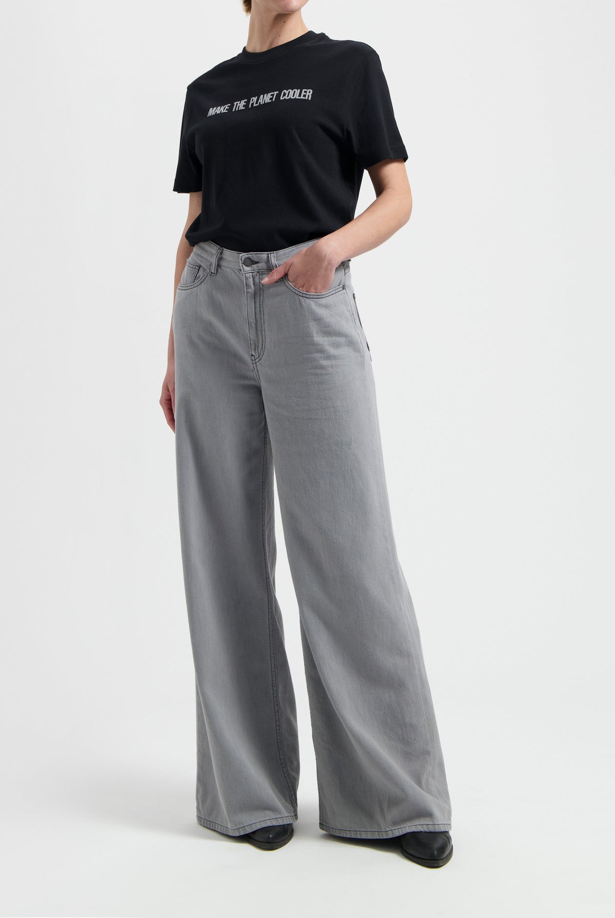 Model wearing a black slogan t-shirt and light gray wide-leg jeans, showcasing casual chic fashion style.