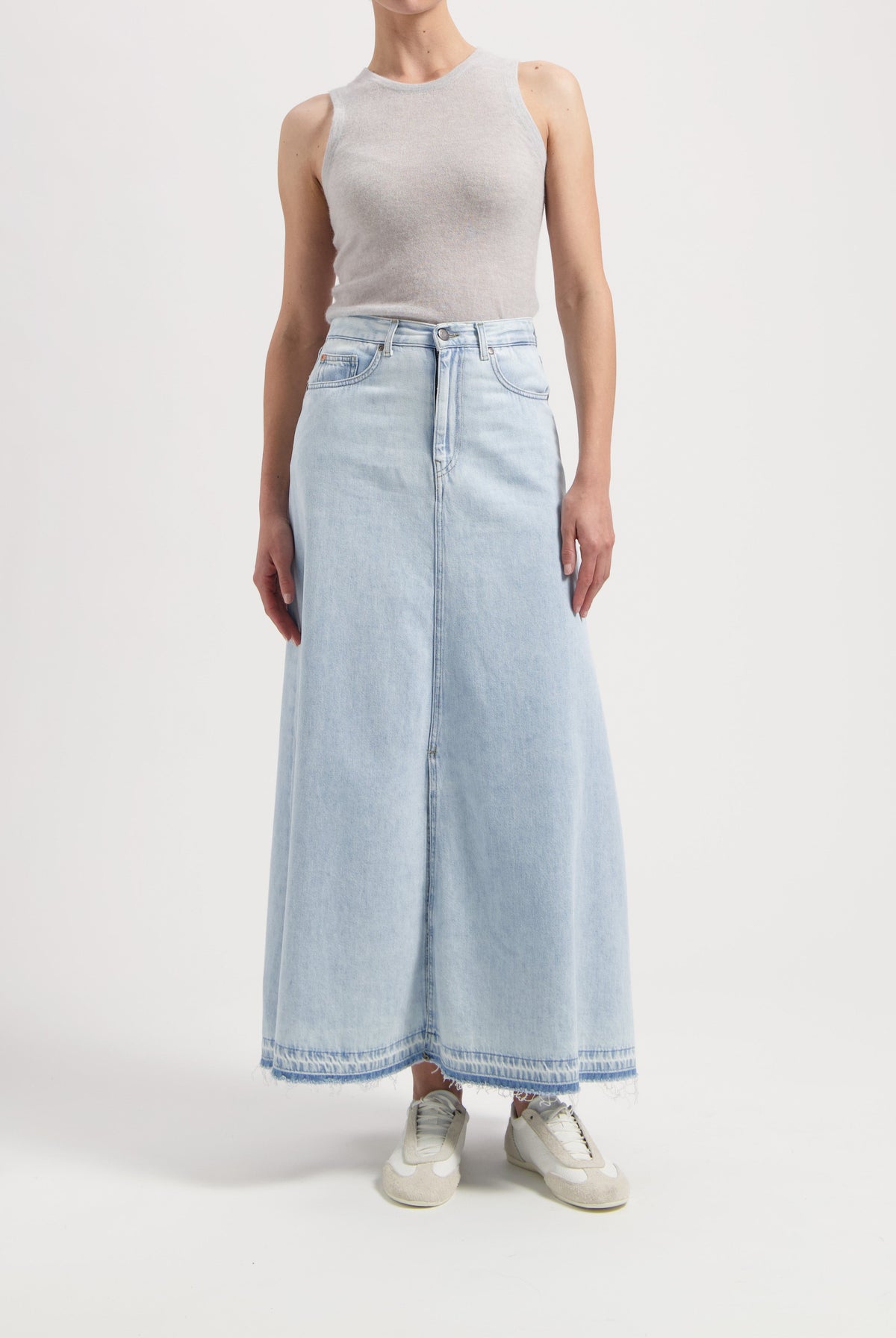 Light blue denim maxi skirt paired with a sleeveless gray top, styled with casual beige sneakers.