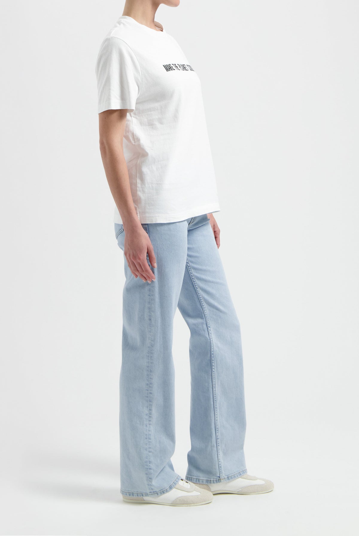 A casual outfit featuring a white cotton t-shirt with text, paired with light blue wide-leg jeans and white sneakers.