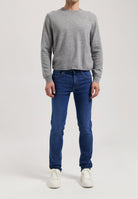 Sustainable MUD Jeans in deep blue denim, crafted ethically with organic cotton, paired with a casual gray t-shirt.