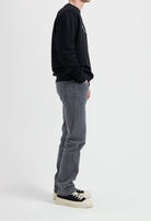 Sustainable MUD Jeans in light blue denim, crafted ethically from organic cotton, shown paired with white sneakers.