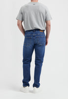 Sustainable MUD Jeans in beige, crafted from organic cotton, offering a slim fit, paired with a casual gray t-shirt.