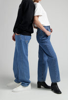 Casual blue jeans outfit with white tee and black sweatshirt, styled with white sneakers and black heeled boots.